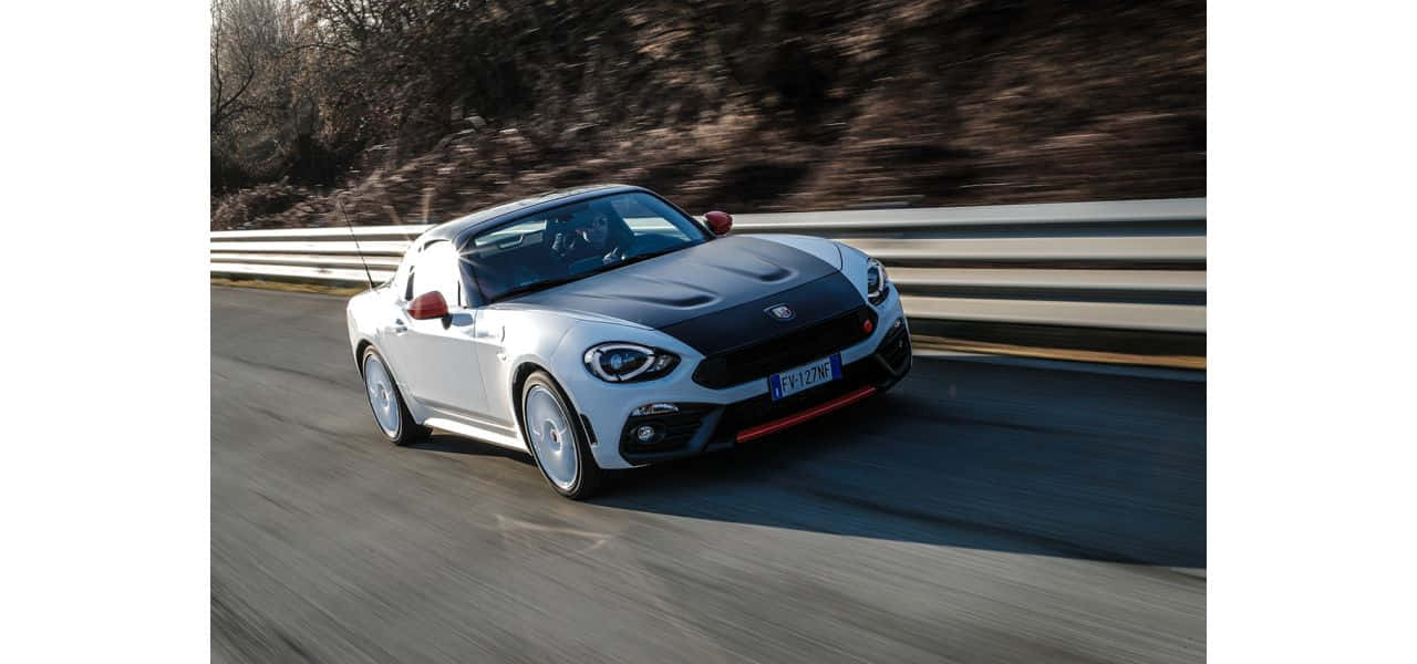 Fiat 124 Spider Cruising On A Scenic Road Wallpaper