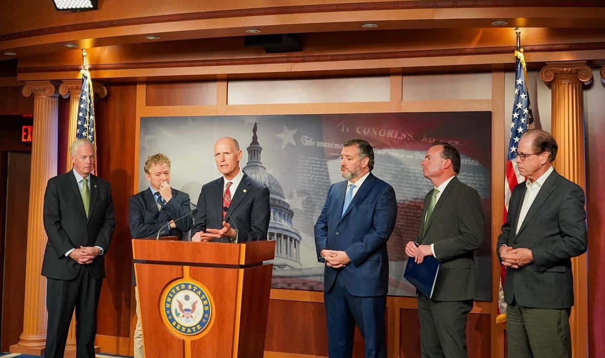 Florida Senator Rick Scott Delivering Speech At Podium Wallpaper