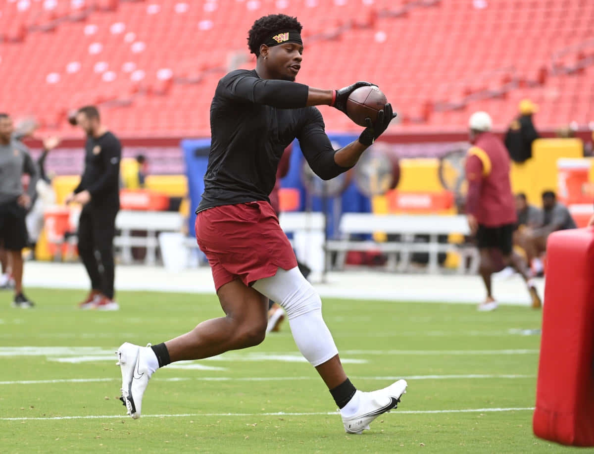 Football Player Catching Ball During Warmup Wallpaper