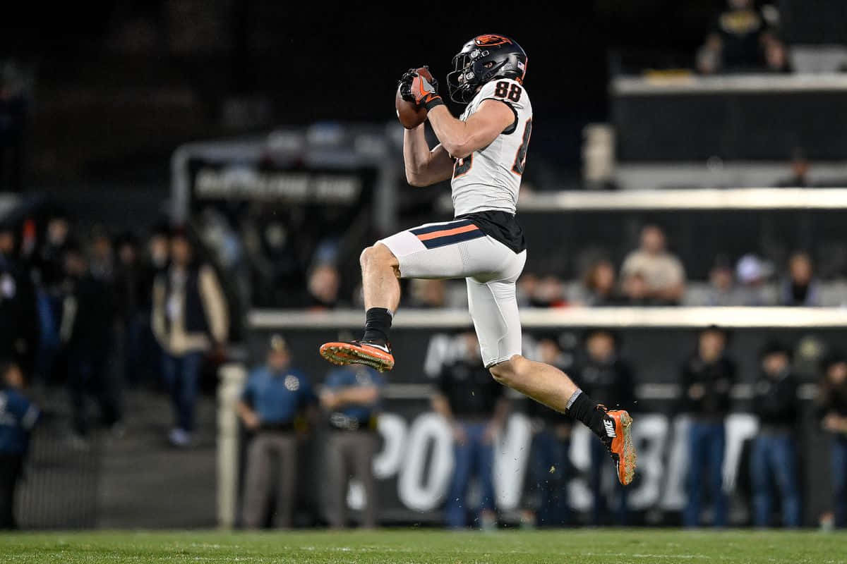 Football Player Catching Ball In Midair Wallpaper