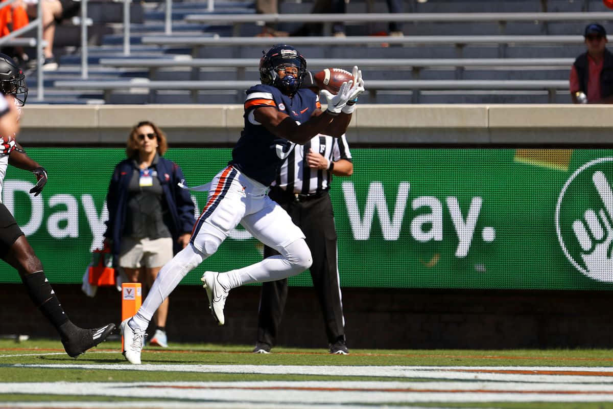 Football Player Catching Ball In Midair Wallpaper