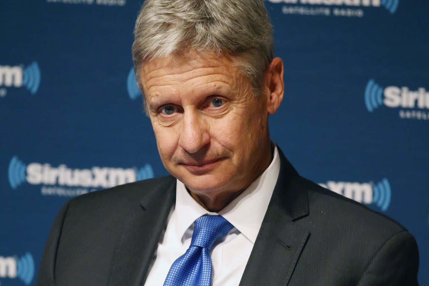 Gary Johnson Smiling And Wearing A Sophisticated Blue Tie Wallpaper