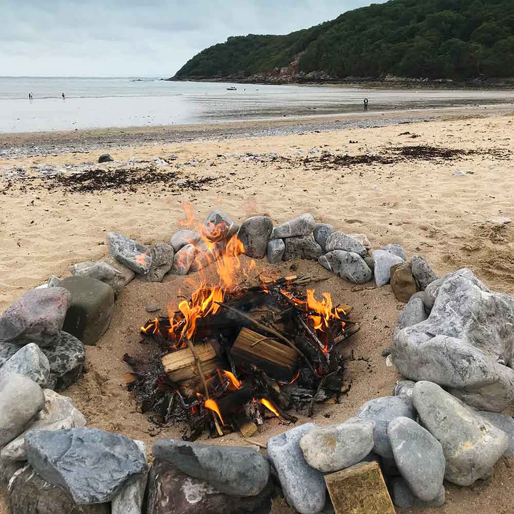 Glowing Beach Campfire Under A Stunning Sunset Wallpaper