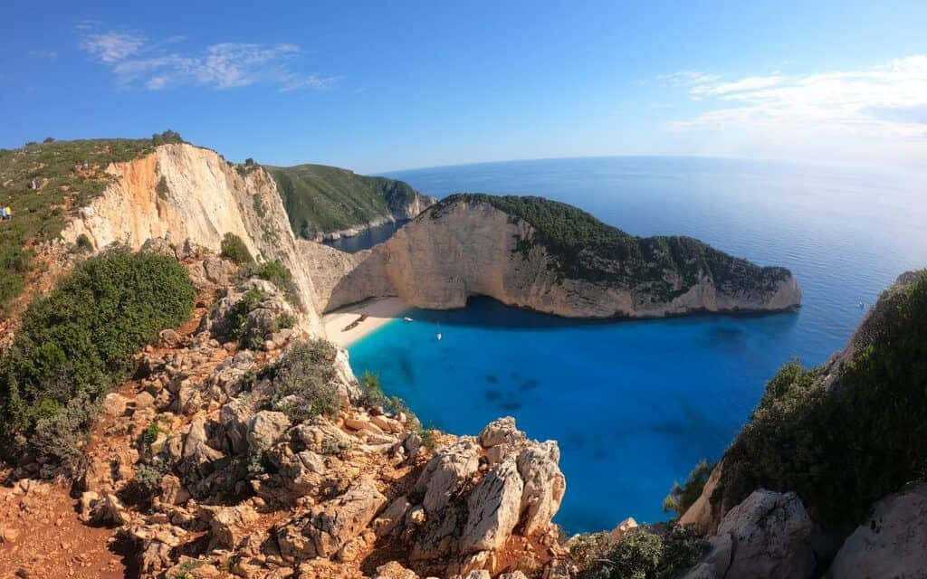 Idyllic Greek Island With Crystal Clear Waters, Vibrant Blue Skies In The Background Wallpaper