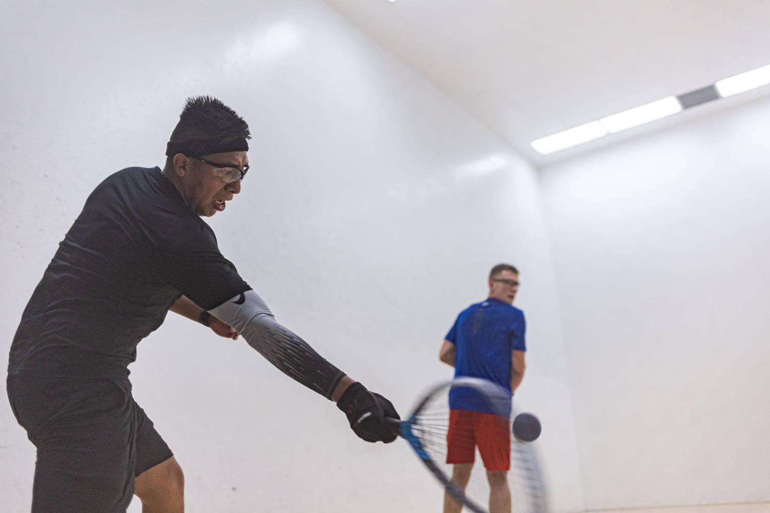 Intense Racquetball Match - Man Forcefully Hitting Ball Wallpaper