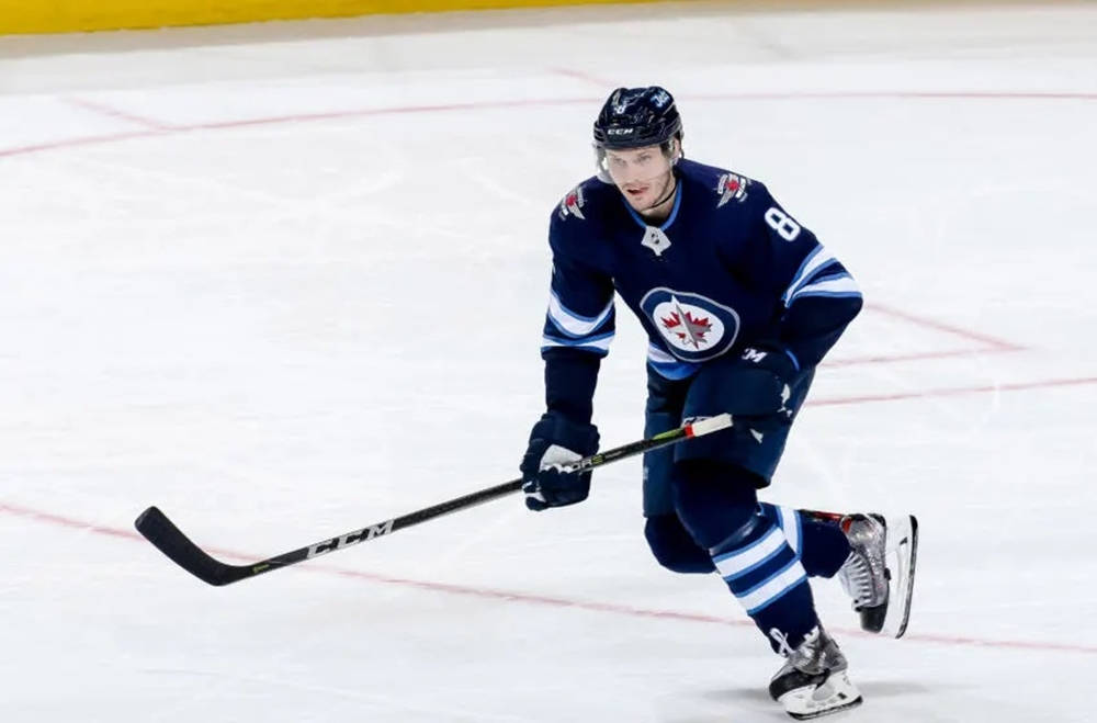 Jacob Trouba Gliding On Ice With Raised Hockey Stick Wallpaper