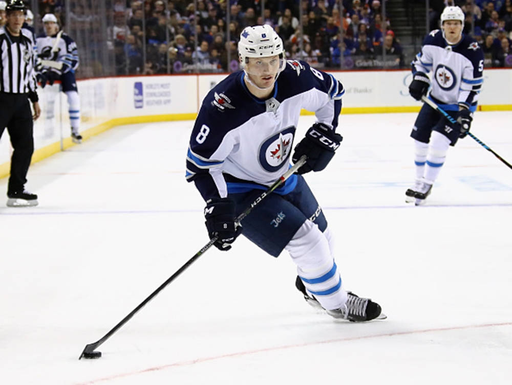 Jacob Trouba Leaning To The Right While Holding Hockey Stick Wallpaper