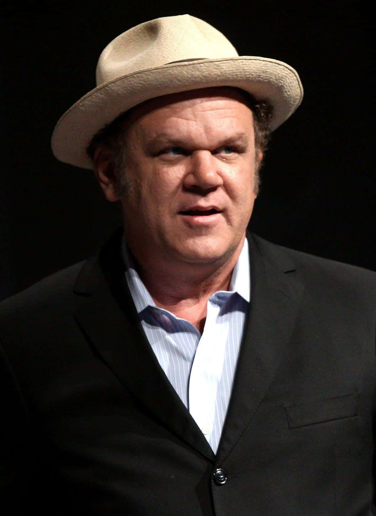 John C. Reilly Striking A Casual Pose On A Gray Background Wallpaper