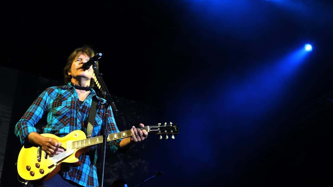 John Fogerty Performing Liveon Stage Wallpaper