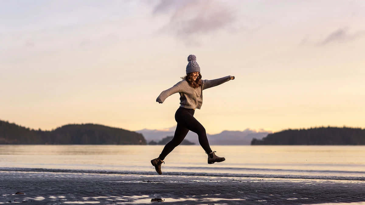 Joyful Beach Skippingat Sunset Wallpaper