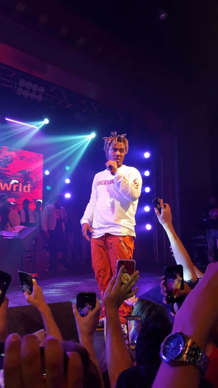 Juice Wrld Standing With His Iconic Skullcandy And Iphone Wallpaper