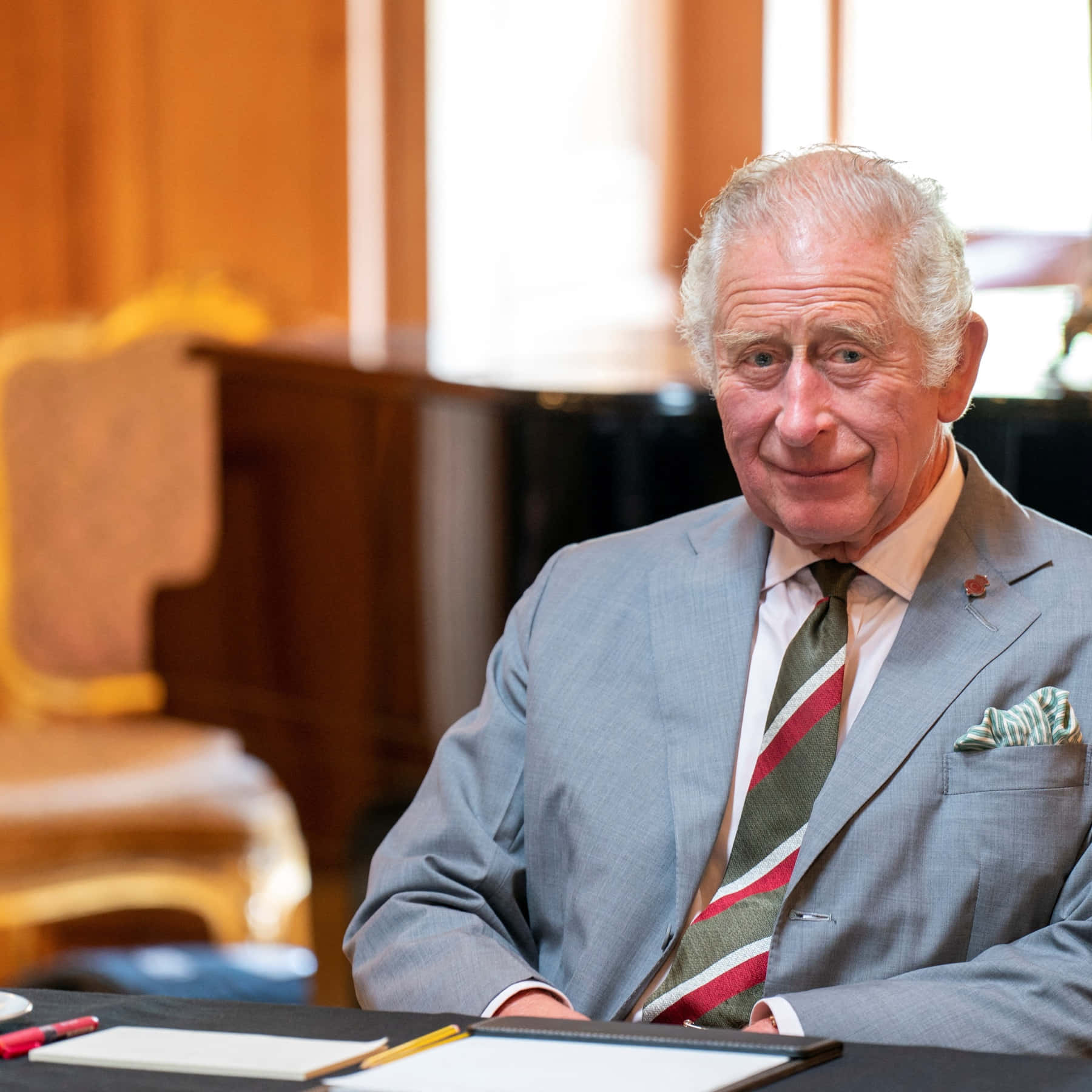 King Charles Iii Smirking Behind Desk Wallpaper