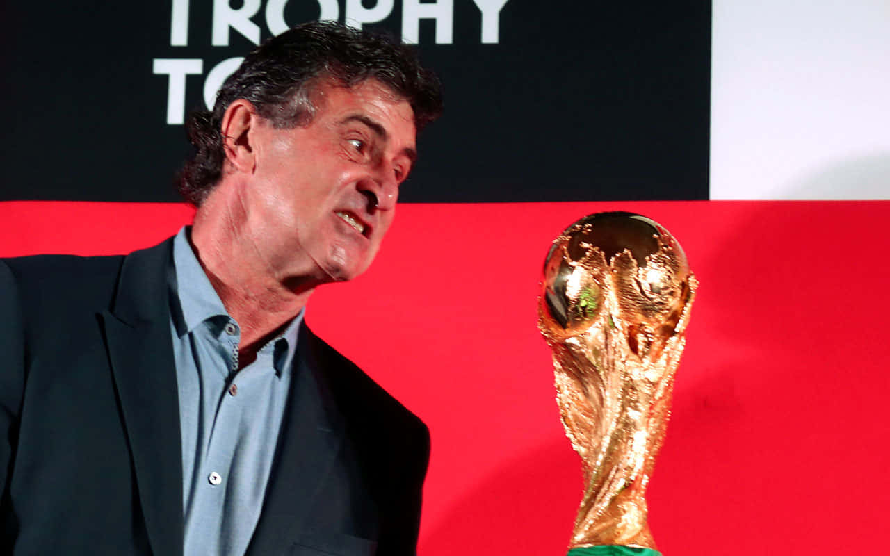 Legendary Footballer Mario Kempes Holding Fifa World Cup Trophy Wallpaper