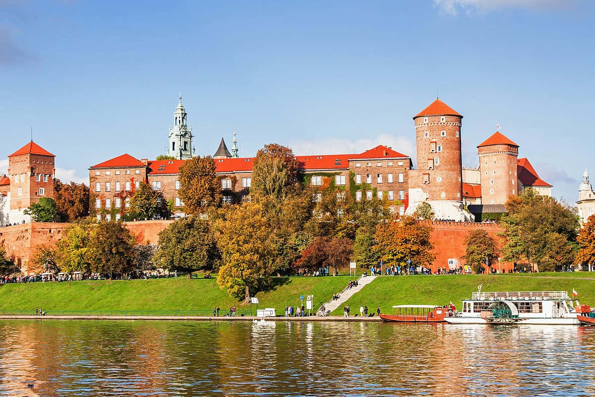 Majestic View Of Wawel Castle With Parked Boats On Vistula River, Poland Wallpaper