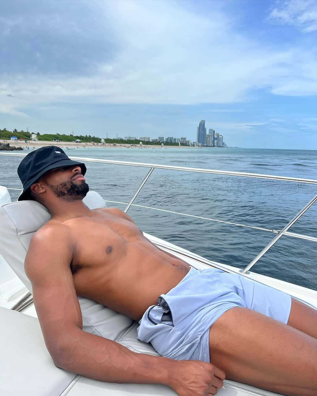 Man Relaxingon Yachtwith City Skyline Wallpaper