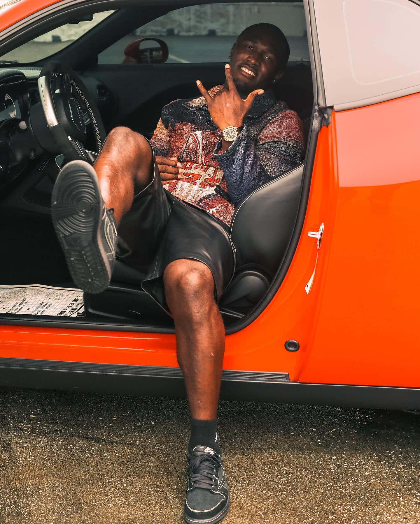 Man Seatedin Orange Car Flashing Peace Sign Wallpaper