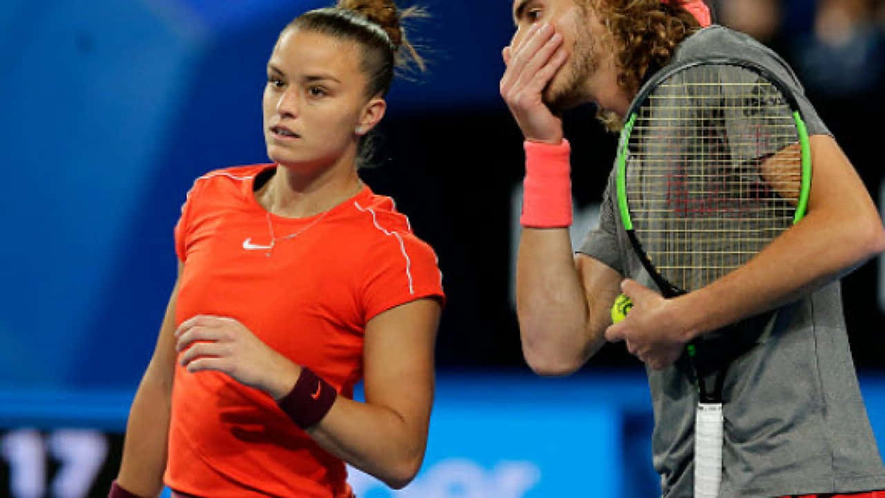 Maria Sakkari And Stefanos Tsitsipas Whispering During A Tennis Match Wallpaper