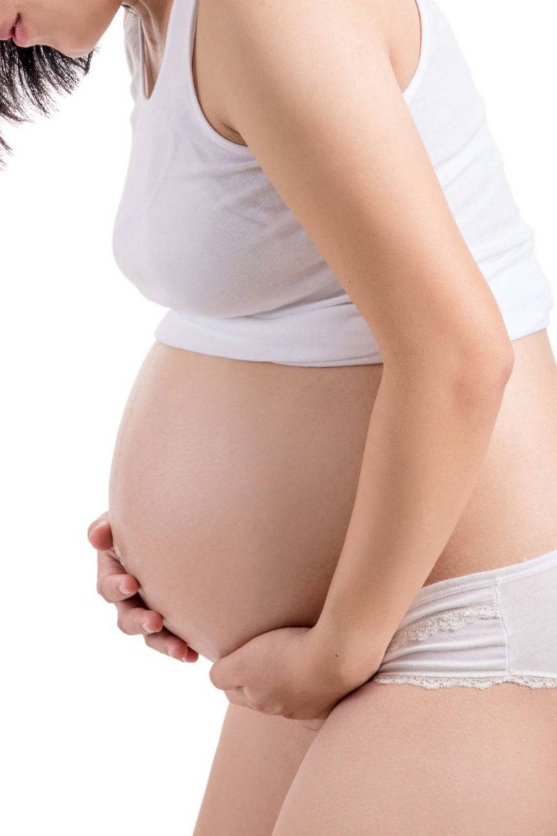 Mother's Embrace: A Pregnant Woman Lovingly Massaging Her Belly Against A White Background Wallpaper