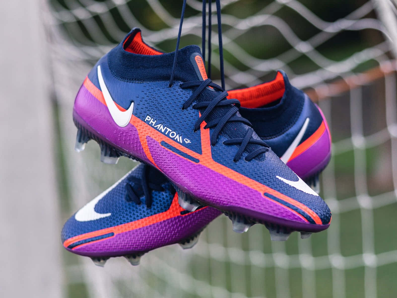 Nike Phantom Soccer Cleats Hanging Against Net Wallpaper