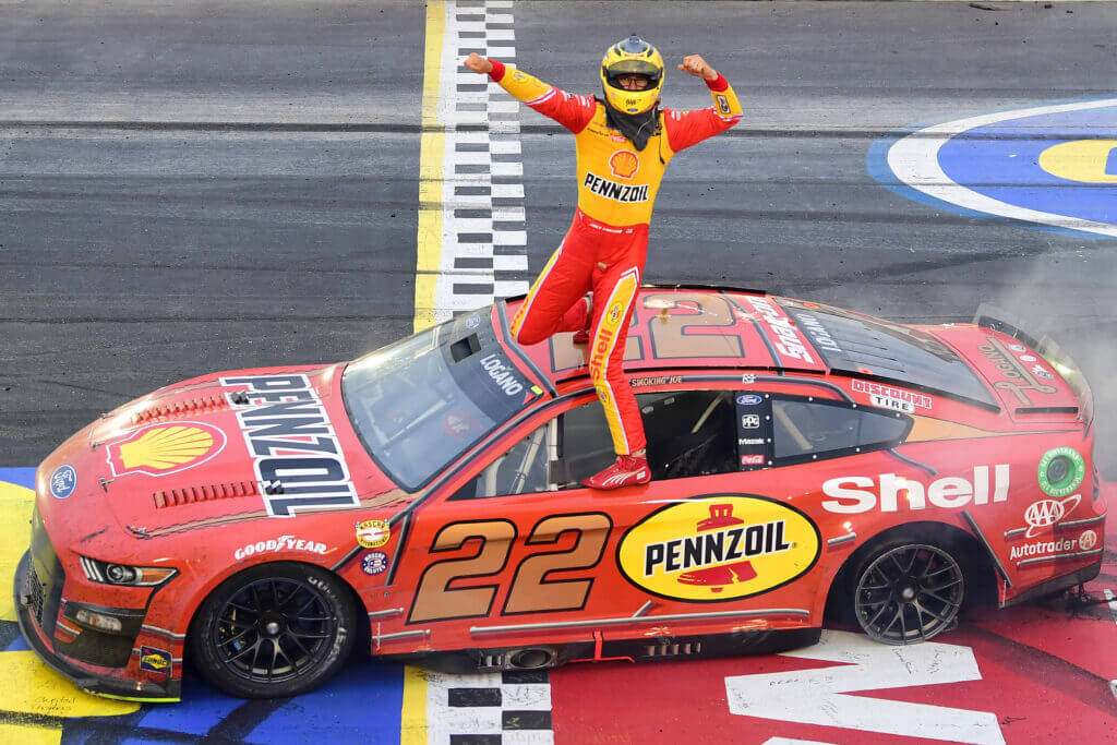 Outgoing Nascar Star - Joey Logano Leaning On His Race Car Wallpaper