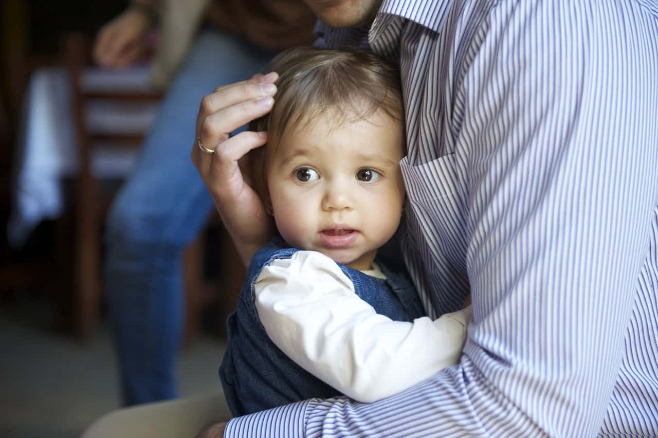 Photo Of A Tangible Baby Being Hug By An Older Person Wearing Striped Long Sleeve Wallpaper