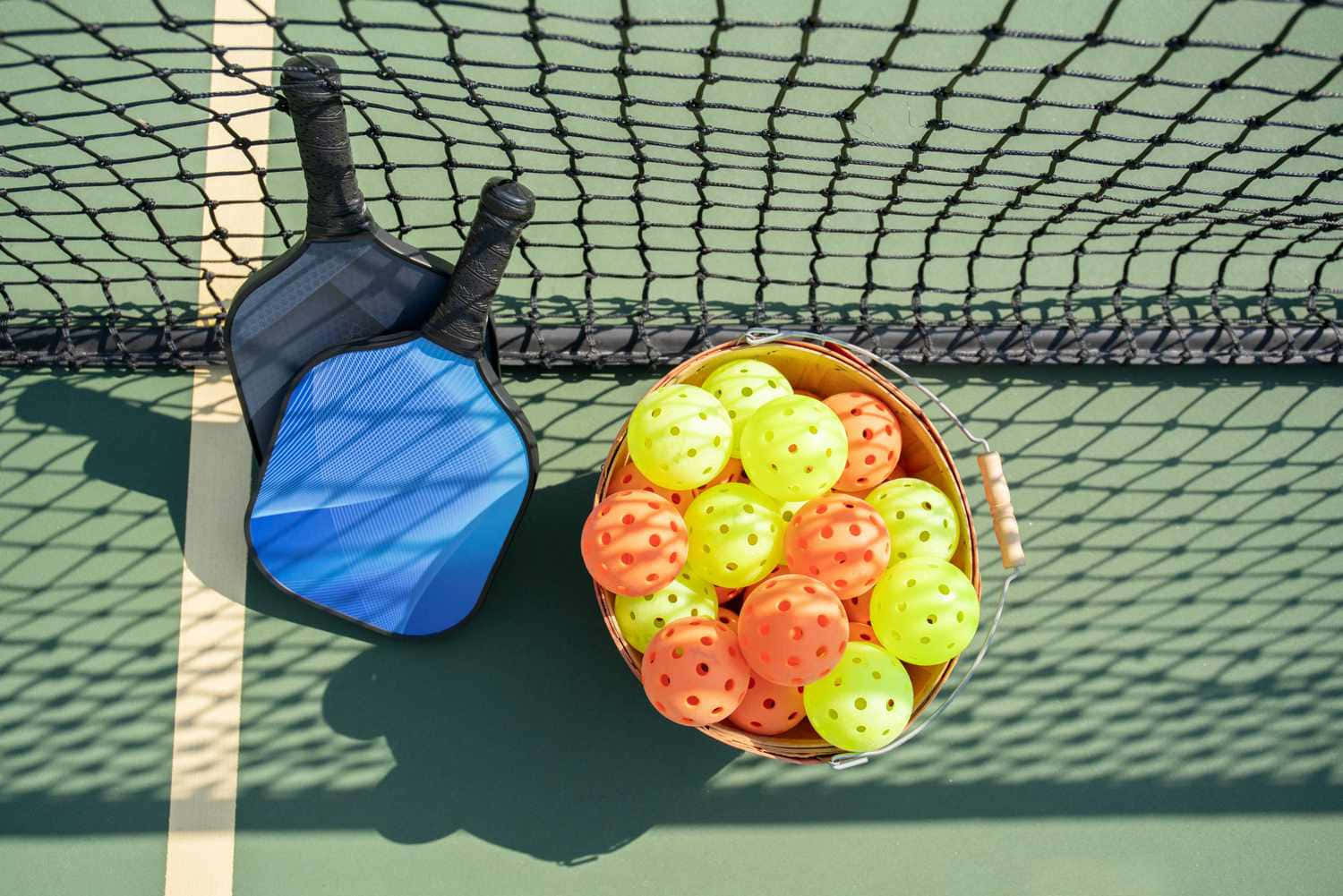 Pickleball Paddlesand Balls Nextto Net Wallpaper