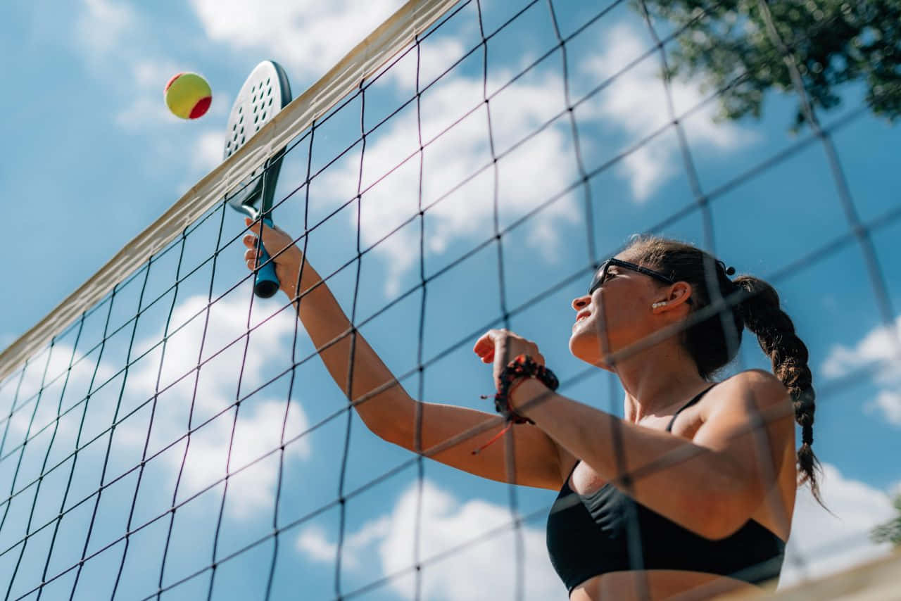 Players Enjoying A Beach Tennis Match On A Sunny Day Wallpaper