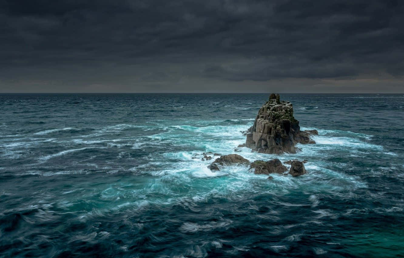 Powerful Waves Crashing Against Rocky Shoreline During A Raging Ocean Storm Wallpaper