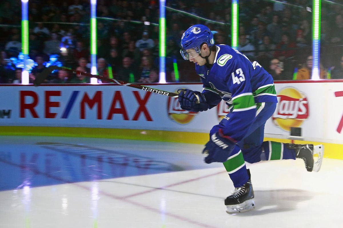 Quinn Hughes Gliding On Ice Under The Spotlight Wallpaper