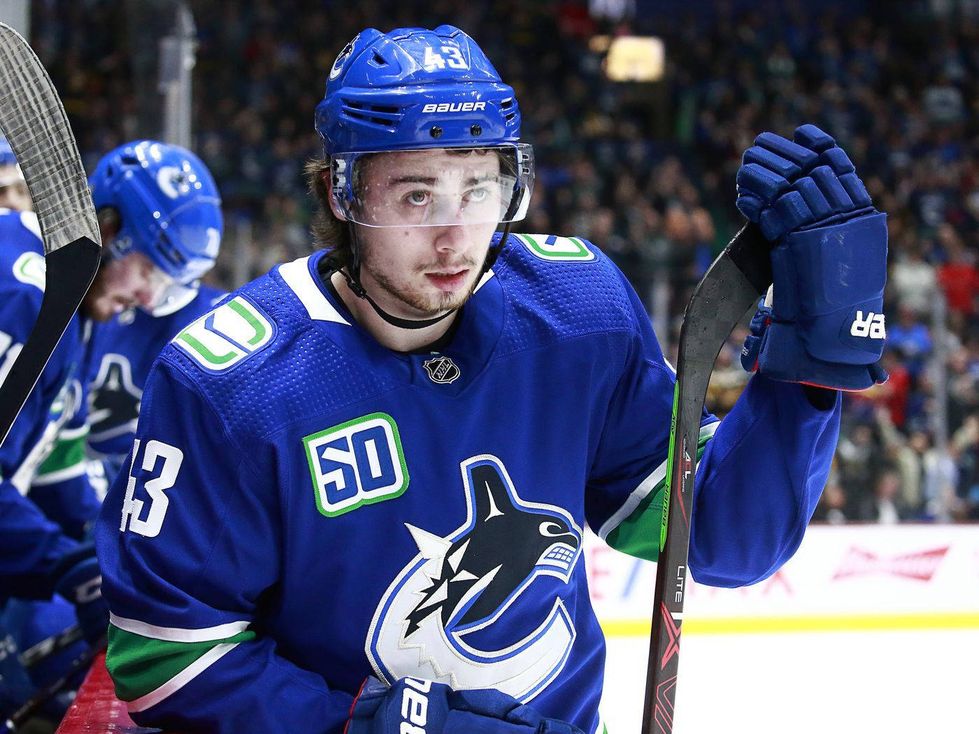 Quinn Hughes Looking Up While Holding Hockey Stick Blade Wallpaper