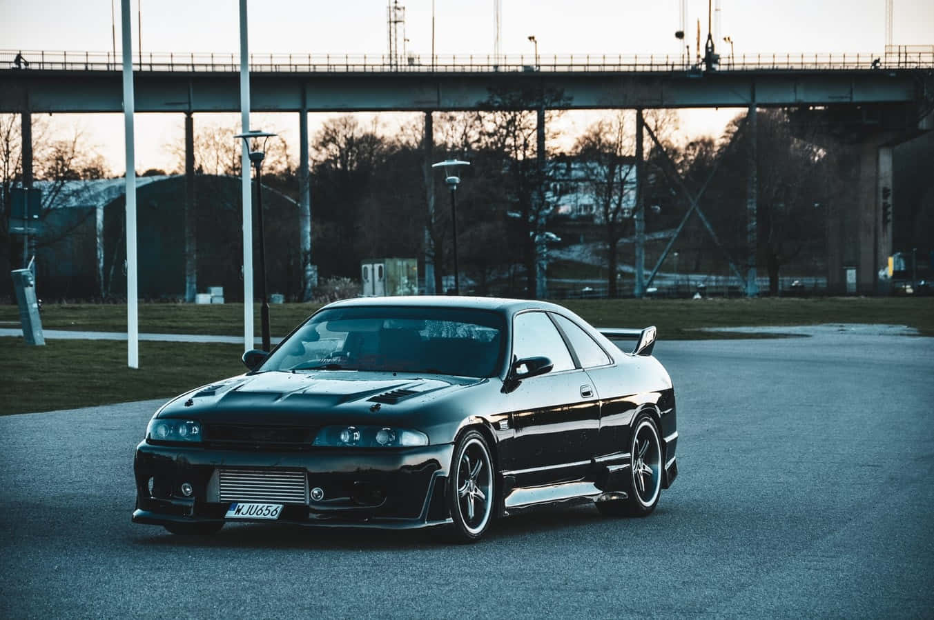 R33 Gtr Black Lowrise Driving On The Road Wallpaper