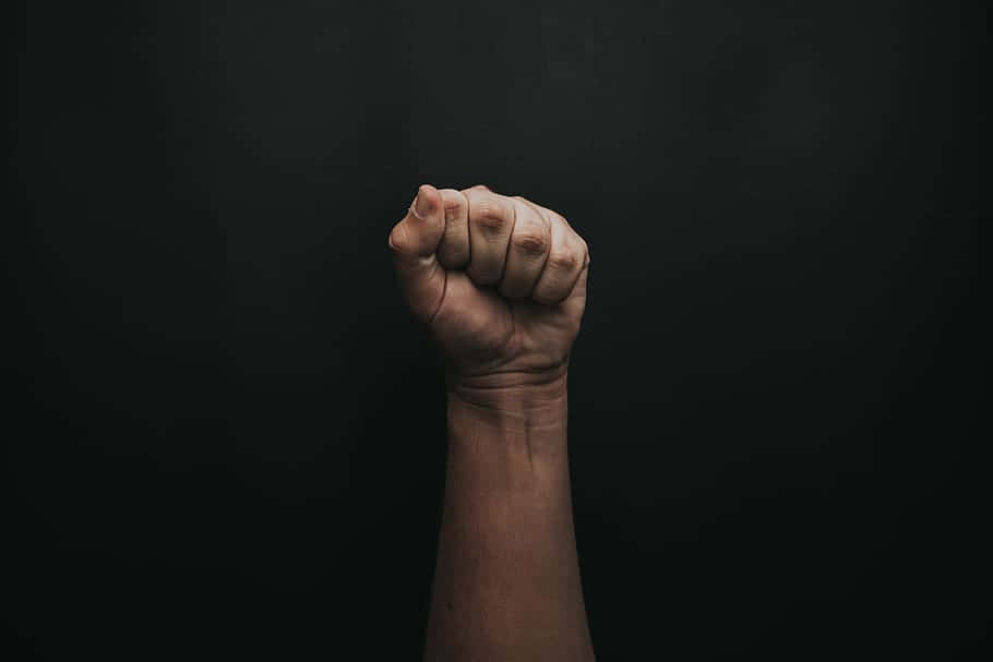 Raised Fist Against Black Background Wallpaper