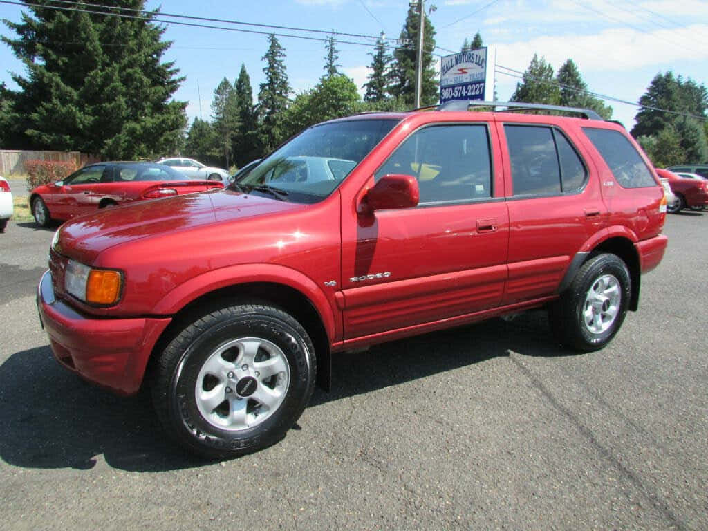 Red Isuzu Rodeo S U V Parked Outdoors Wallpaper