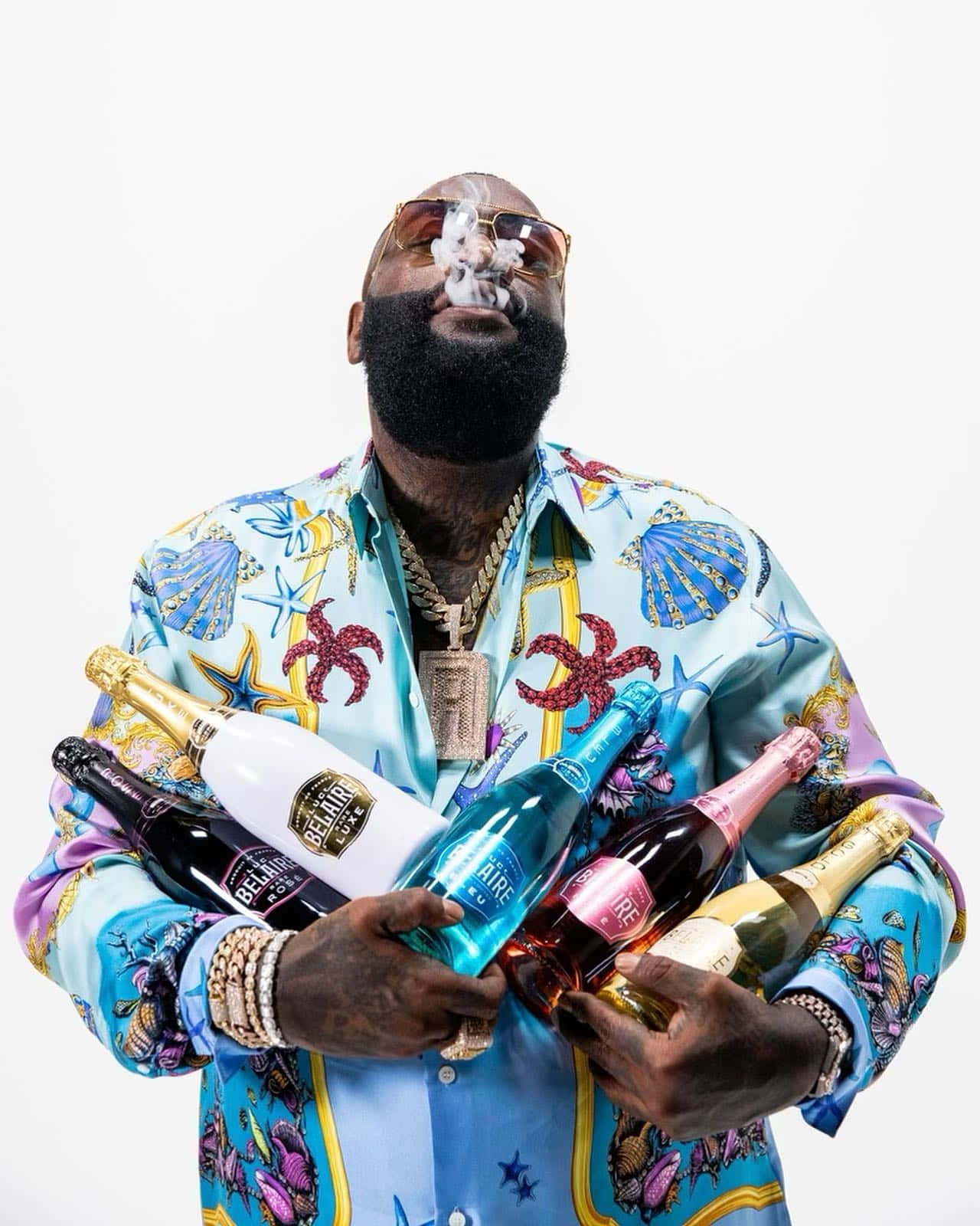 Rick Ross Holding Bottlesand Exhaling Smoke Wallpaper