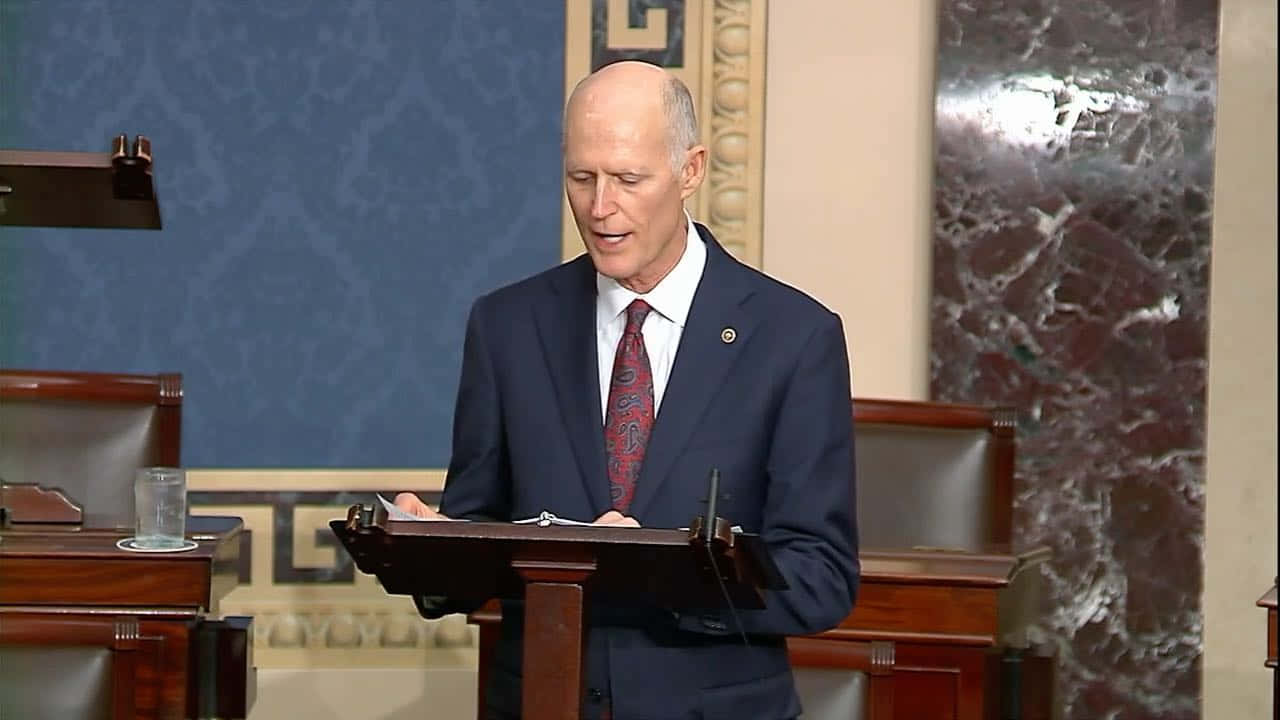 Rick Scott Speaks From A Podium Wallpaper