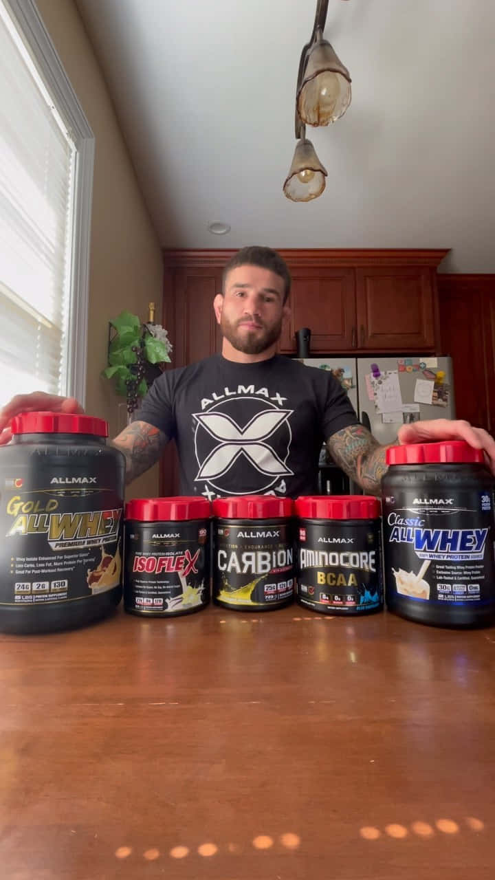 Sean Brady With Protein Powders On Table Wallpaper