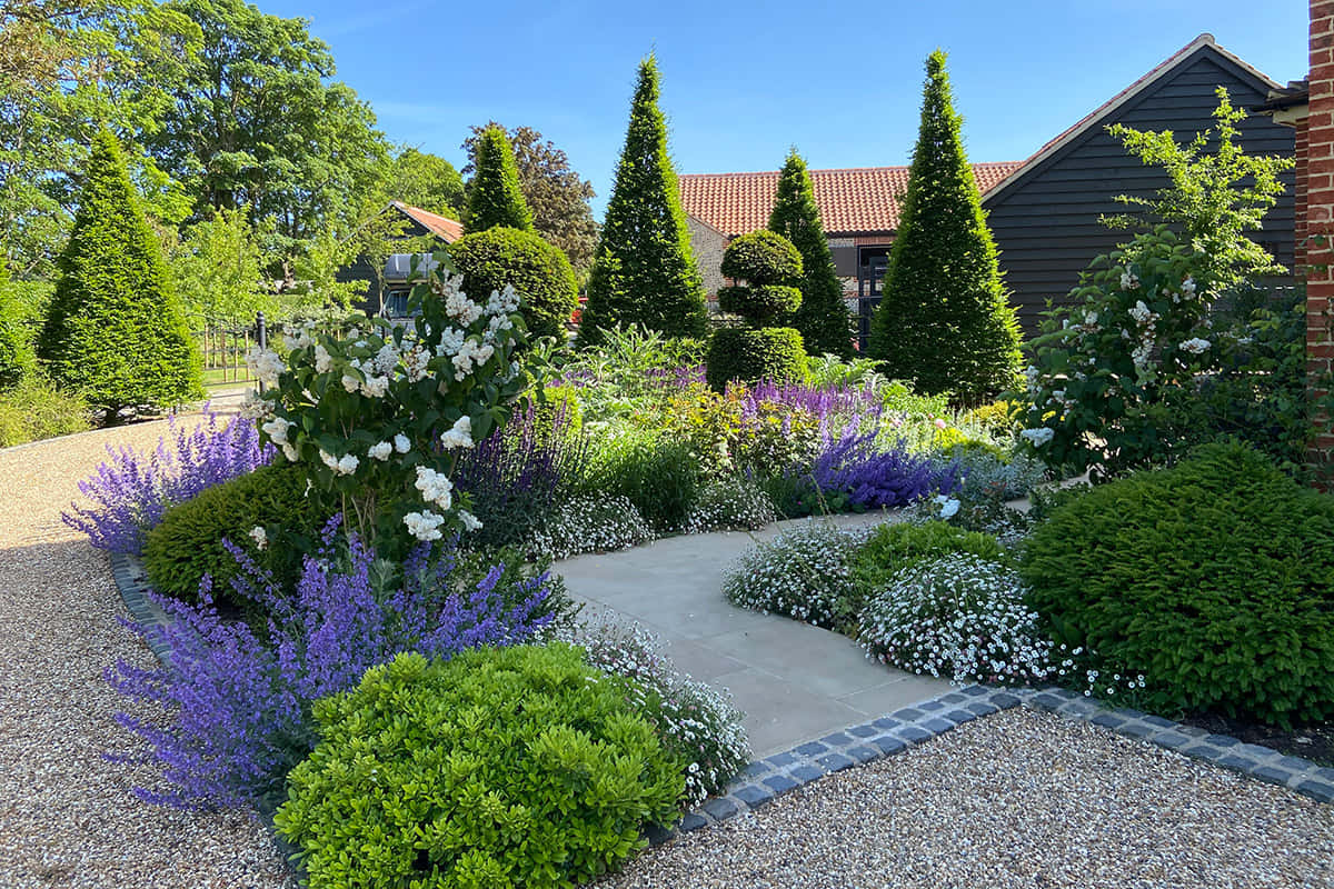 Serene Backyard Garden Featuring Lush Greenery, Vibrant Flowers, And A Calming Water Feature Wallpaper