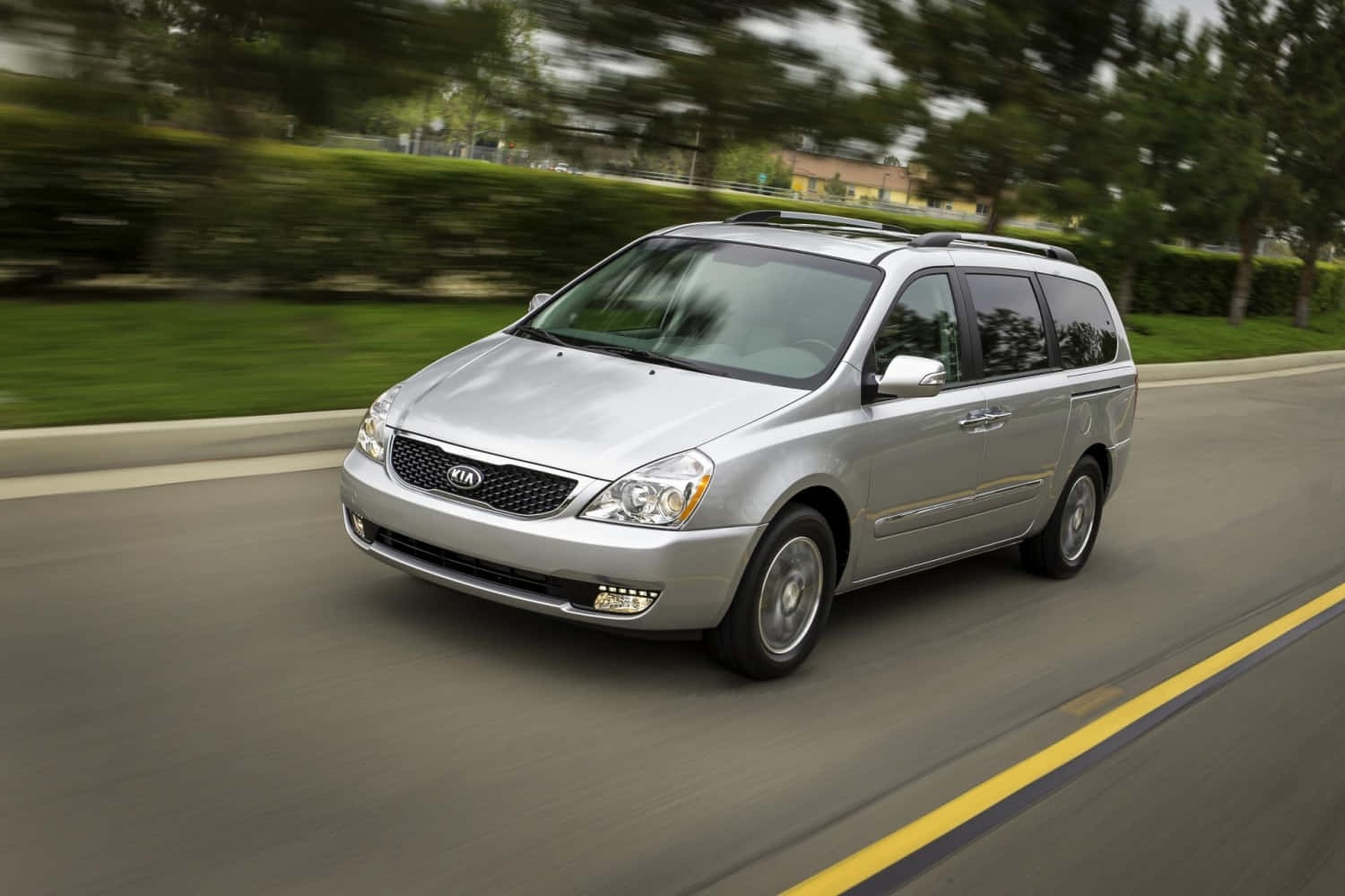 Sleek And Spacious Kia Sedona On A Picturesque Road Wallpaper