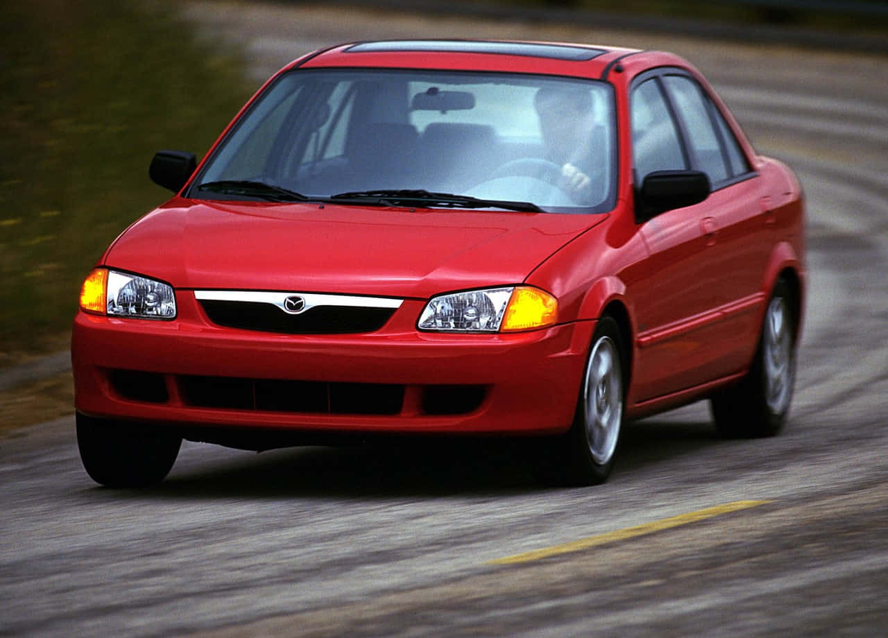 Sleek Mazda Protege Cruising On The Highway Wallpaper