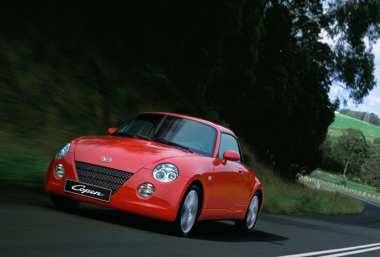 Sleek Red Daihatsu On An Open Road Wallpaper