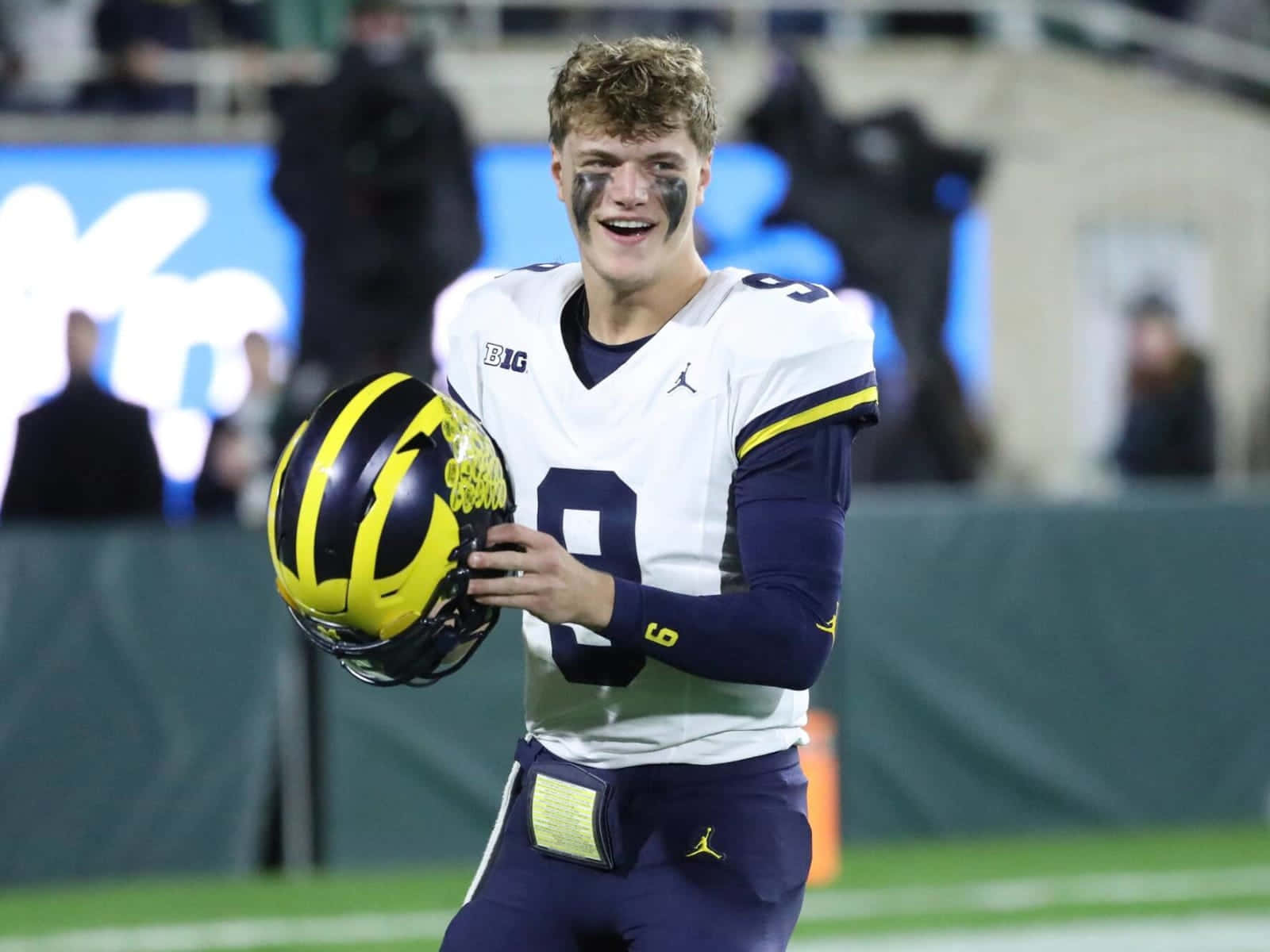 Smiling Football Player Holding Helmet Wallpaper