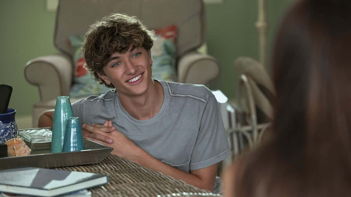 Smiling Young Man At Table Wallpaper