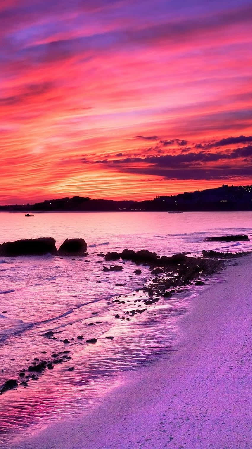 Soak In The Dreamy Pink Sunset With The Waves Lapping At Your Feet. Wallpaper