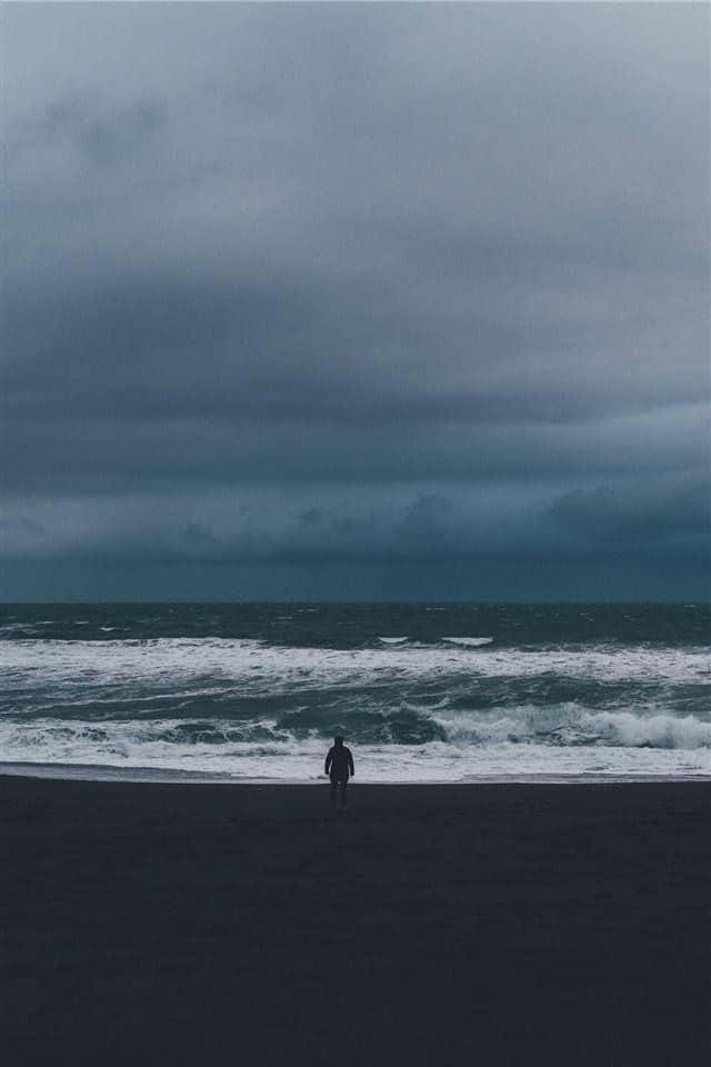 Solitary_ Figure_on_ Stormy_ Shoreline Wallpaper