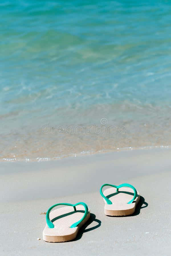 Stylish Beach Sandals On The Sandy Shore Wallpaper