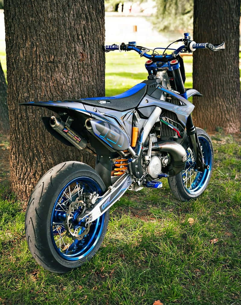 T M Racing Supermoto Parked Between Trees Wallpaper