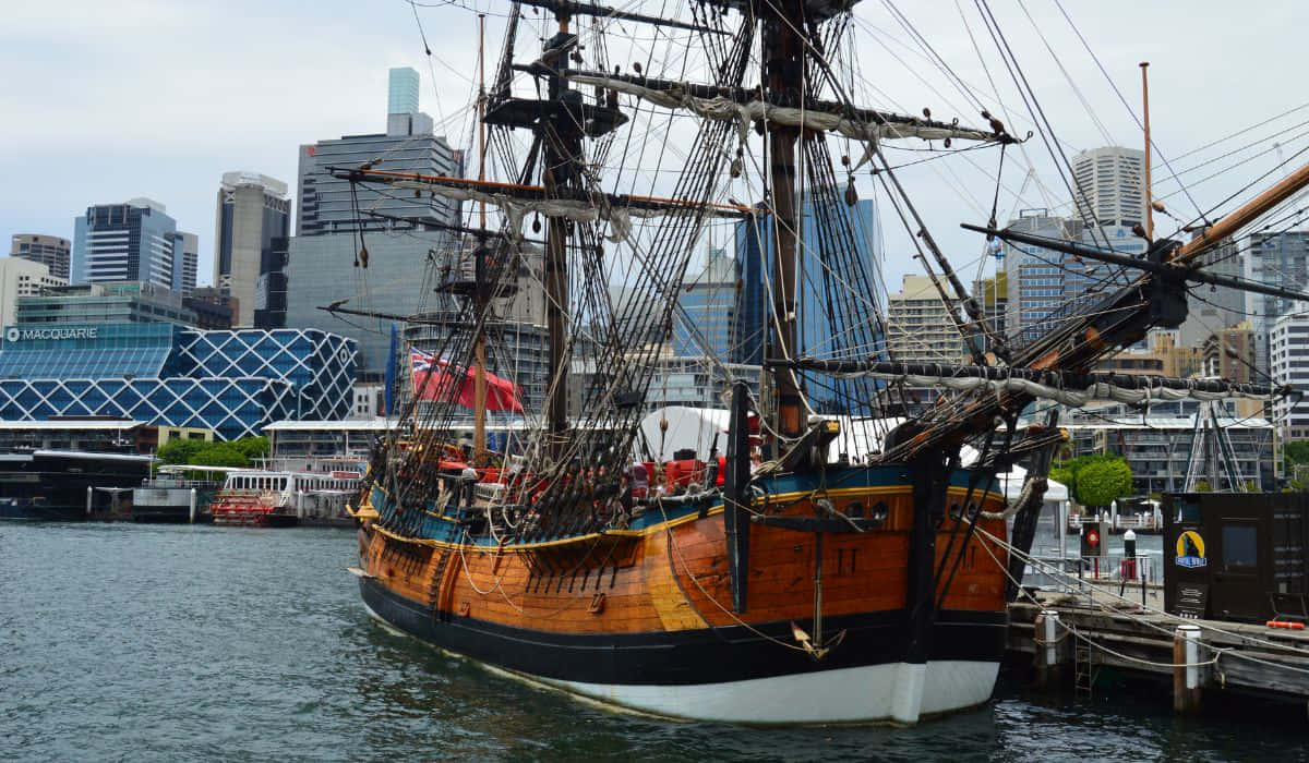 Tall_ Ship_in_ Harbor_with_ City_ Backdrop.jpg Wallpaper