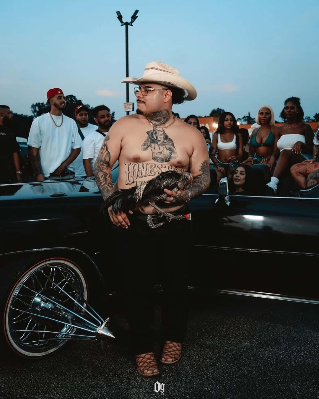 Tattooed Manwith Hatand Iguanaat Car Meet Wallpaper