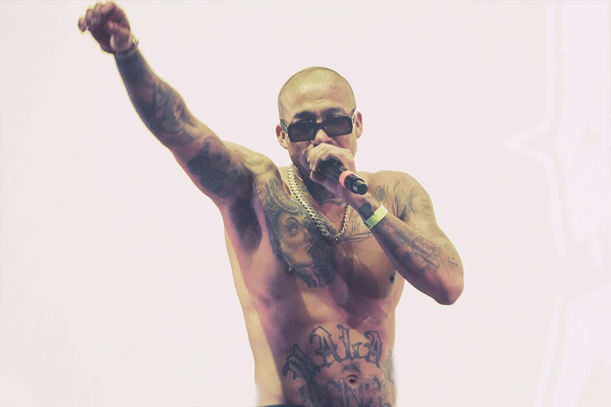 Tattooed Performer Singingon Stage Wallpaper