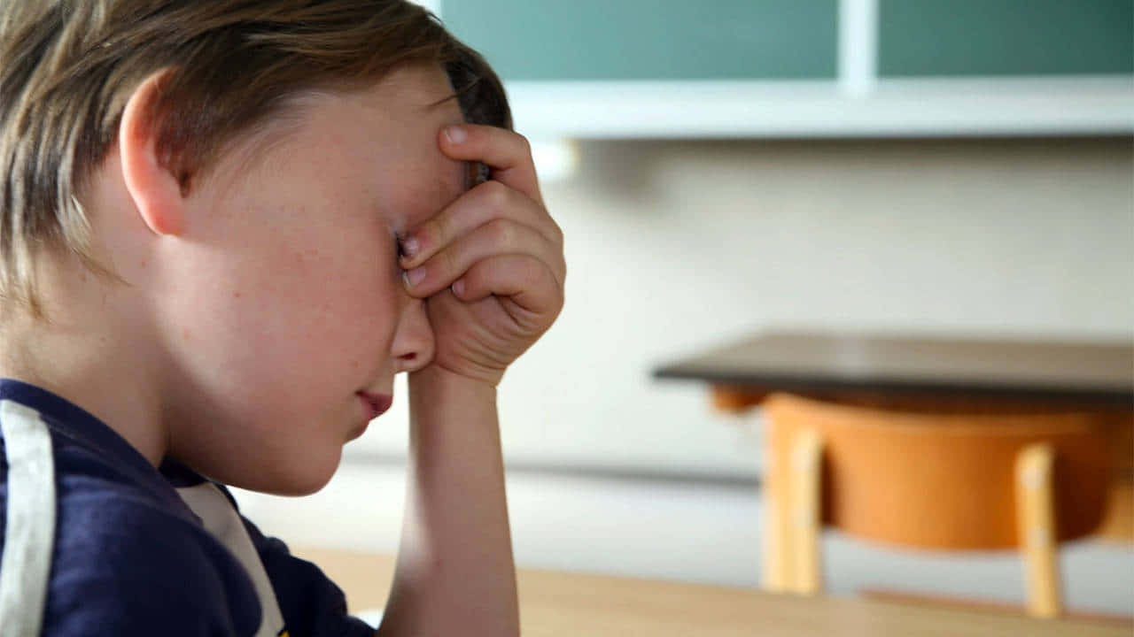 The Overwhelming Side Of Stress: A Distressed And Anxious Child Holding Head In Hands. Wallpaper